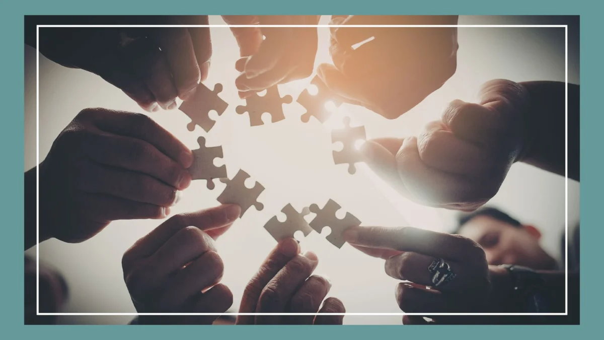 Hände mit Puzzleteilen als Symbol für Zusammenarbeit und Vertrauen im Team